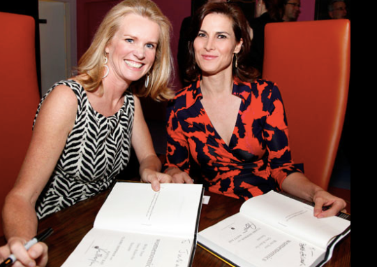 Katty Kay and Claire Shipman, co-authors of The Confidence Code, smiling during a book signing—offering key insights on how to rebuild confidence in yourself as a woman through action over perfection.